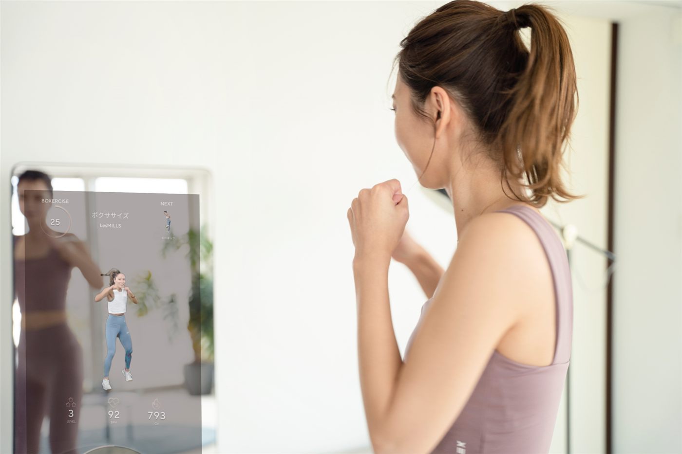 MIRROR FIT.の前でレッスンを受ける女性