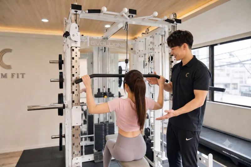 CALM FITのマルチラックで、トレーナーがラットプルダウンをマンツーマン指導